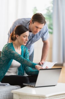 Couple using laptop together to pay bills.
