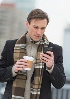 Man in winter clothes looking at phone.