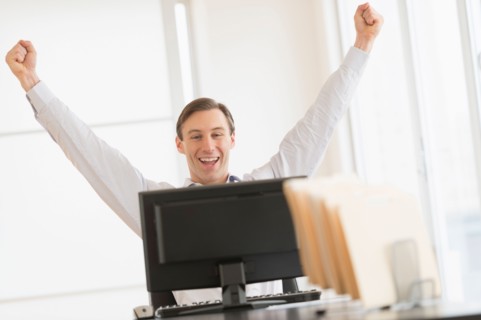 Office worker cheering in front of computer.