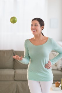 Woman juggling with apple at home.