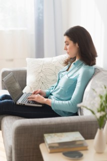Woman sitting on sofa and using laptop.