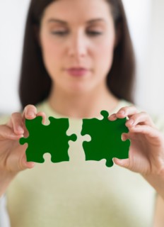 Woman holding green puzzle pieces.