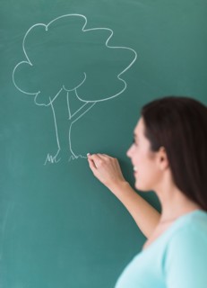 Woman drawing tree on blackboard.