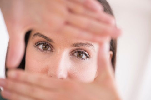 Woman looking at camera through handsframe.