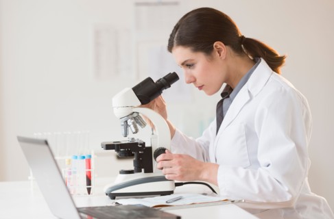 Scientist looking through microscope.