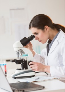 Scientist looking through microscope.