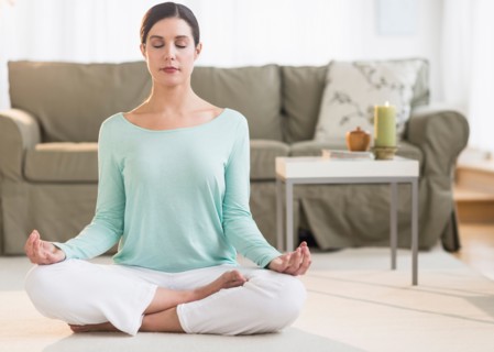 Woman meditating in living room.