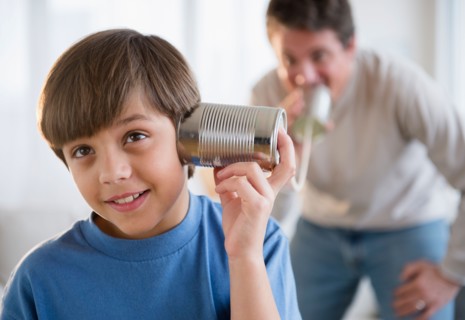 Father and son (8-9) playing with tin can phone