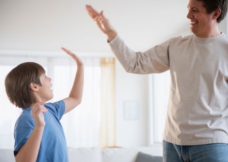 Father and son (8-9) giving each other high five
