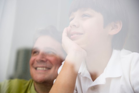 Son (8-9) and father looking through window