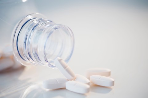 Studio Shot of white pills spilling out of bottle