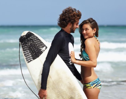 Surfer man and young woman on beach
