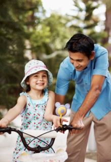 Man assisting girl (6-7) riding bicycle