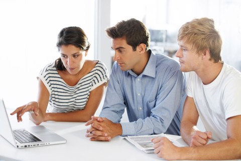Coworkers at table looking at laptop