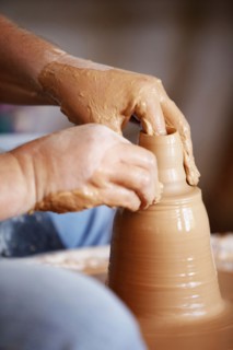 Hands working with clay on potter's wheel