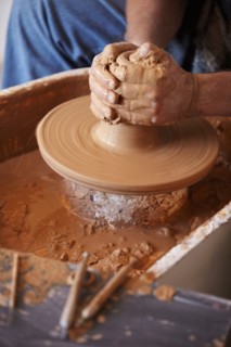Hands working with clay on potter's wheel