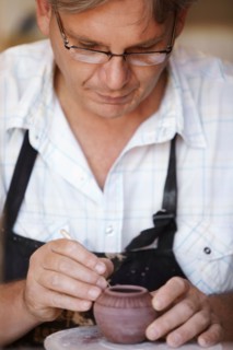 Portrait of male potter carving small vase