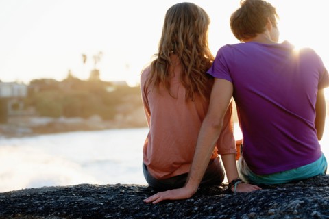 Rear view of young couple sitting at beach