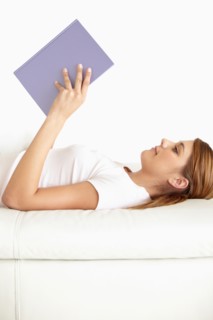 Young woman lying on bed and reading