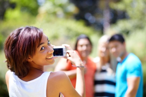 Portrait of young woman taking photo of people