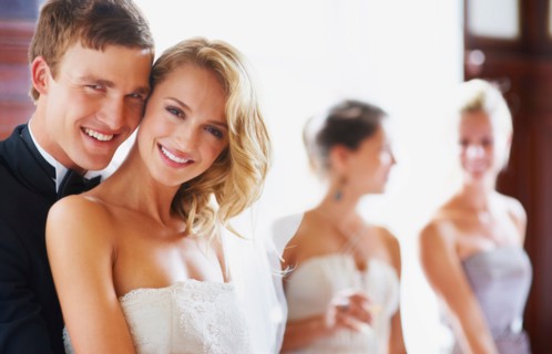 Portrait of newly wed couple, bridesmaids in background