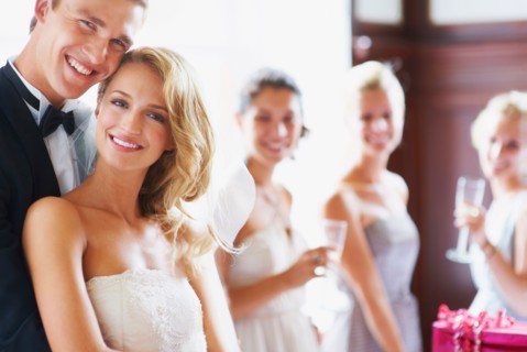 Portrait of newly wed couple, bridesmaids in background