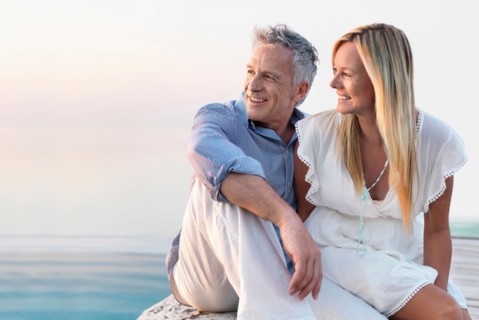 Mature couple sitting by seashore