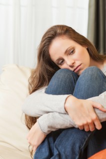 Sad woman sitting on sofa and looking away