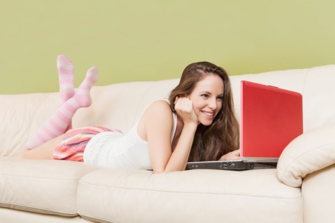 Woman lying on sofa with laptop