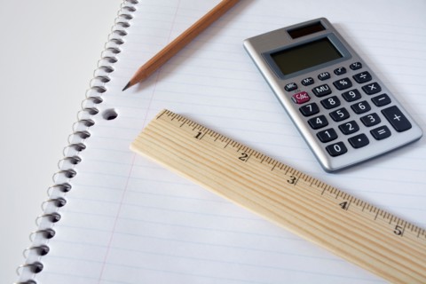 Calculator, ruler and pencil on notebook, studio shot
