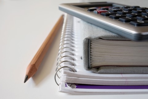 Calculator, textbook and pencil on notebook, studio shot