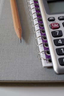 Calculator, textbook and pencil on notebook, studio shot