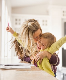 Mother kissing daughter (6-7) during doing homework