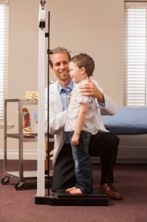 Boy (2-3) on scale in doctor's office