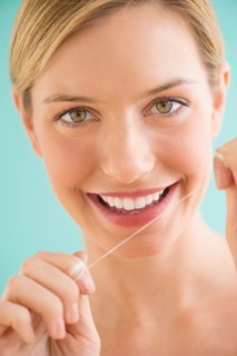 Portrait of woman flossing teeth.