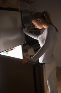 Woman opening fridge at night.