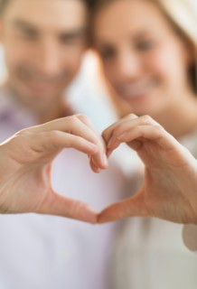 Couple making heart shape with hands.