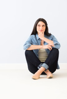 Studio portrait of young woman sitting on floor.