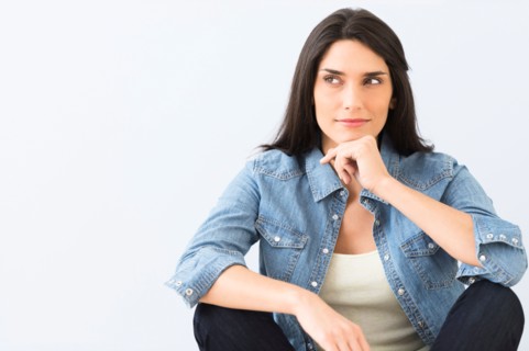 Studio portrait of young woman sitting on floor.