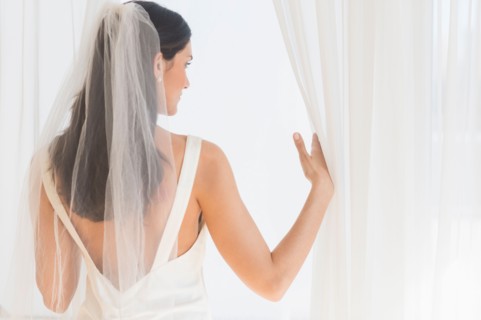 Bride looking through window.