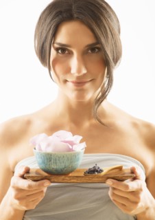 Woman holding tray with scented flower.