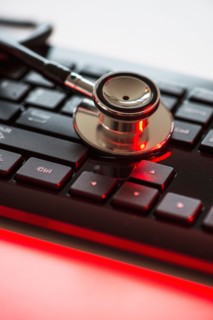 Close up of computer keyboard and stethoscope, studio shot.