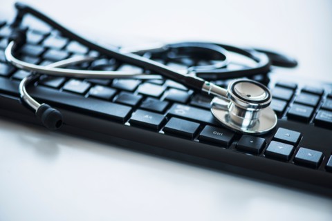 Close up of computer keyboard and stethoscope, studio shot.