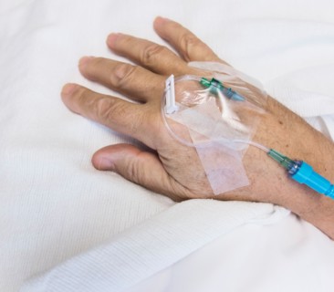 Close up of hand of elderly patient with IV drip attached.