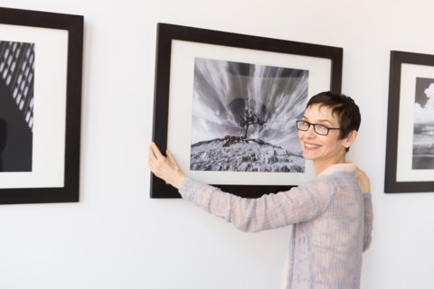 Woman hanging photographs in art gallery.