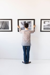 Woman hanging photographs in art gallery.