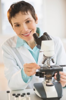 Portrait of smiling woman working with microscope in laboratory.
