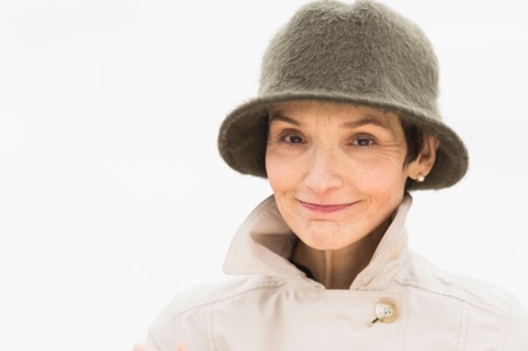Portrait of smiling woman wearing raincoat and hat.