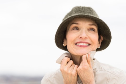 Portrait of smiling woman wearing raincoat and hat.