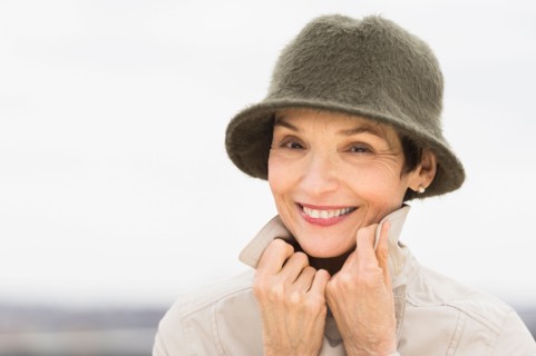 Portrait of smiling woman wearing raincoat and hat.